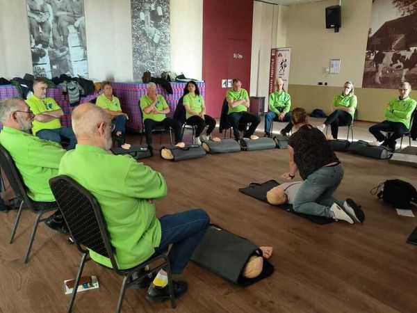 Een groep vrijwilligers aanschouwen de reanimatie les