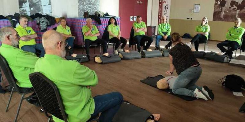 Een groep vrijwilligers aanschouwen de reanimatie les