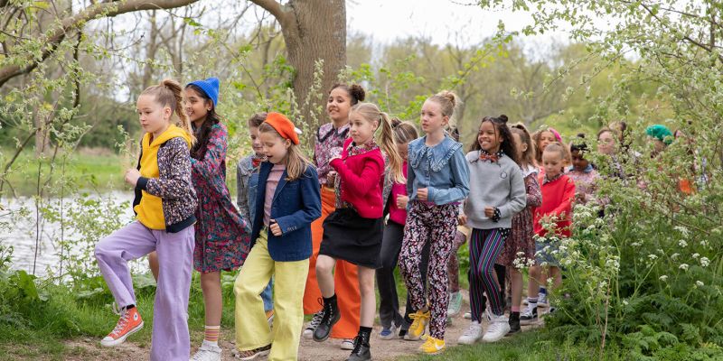 Kinderen wandelen vrolijk langs een vijver